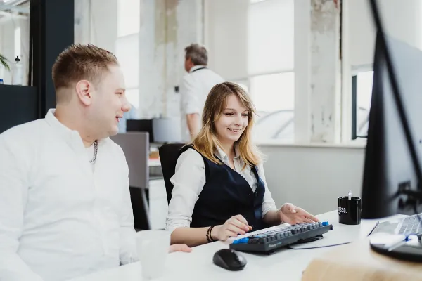 Two people at the office talking behind the desktop about work.
