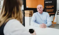 A professional man in a white shirt focuses on his laptop in a modern studio office, representing the focused and transparent nature of modern EU recruitment practices.