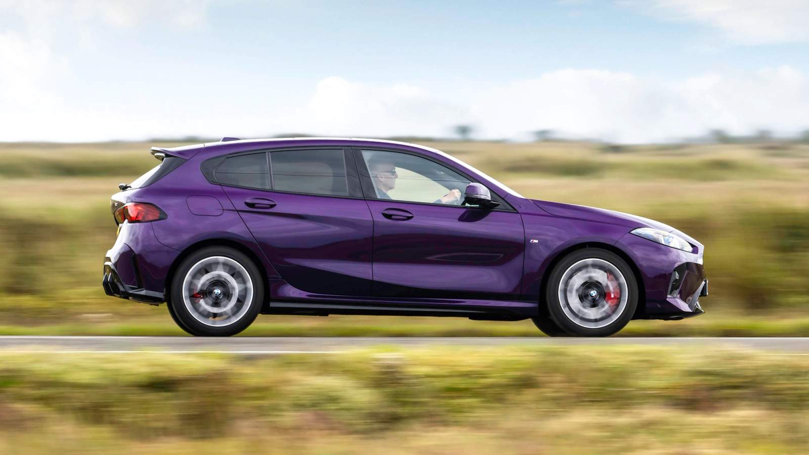 Purple BMW 1 Series driving on a country road