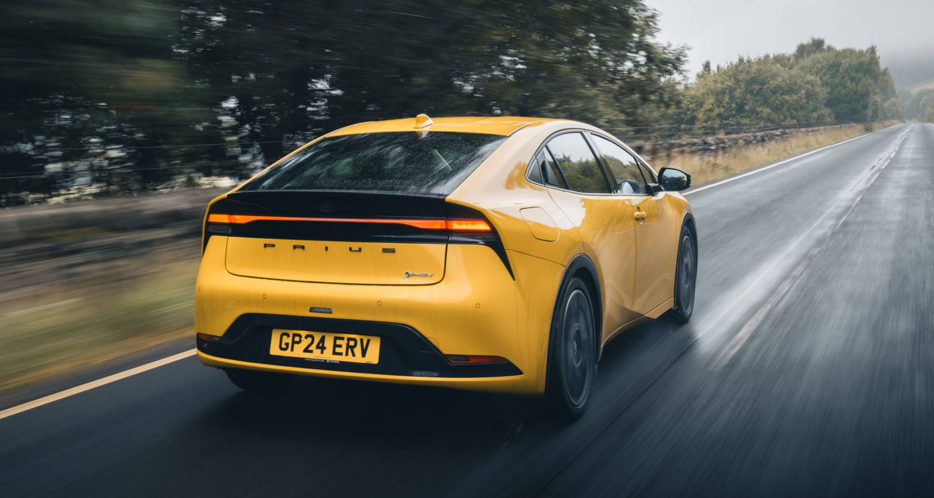 Yellow Toyota Prius driving on a wet road