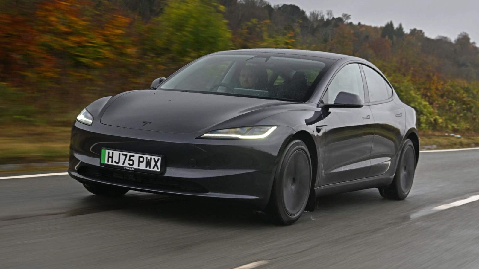Dark grey Tesla Model 3 driving in the rain
