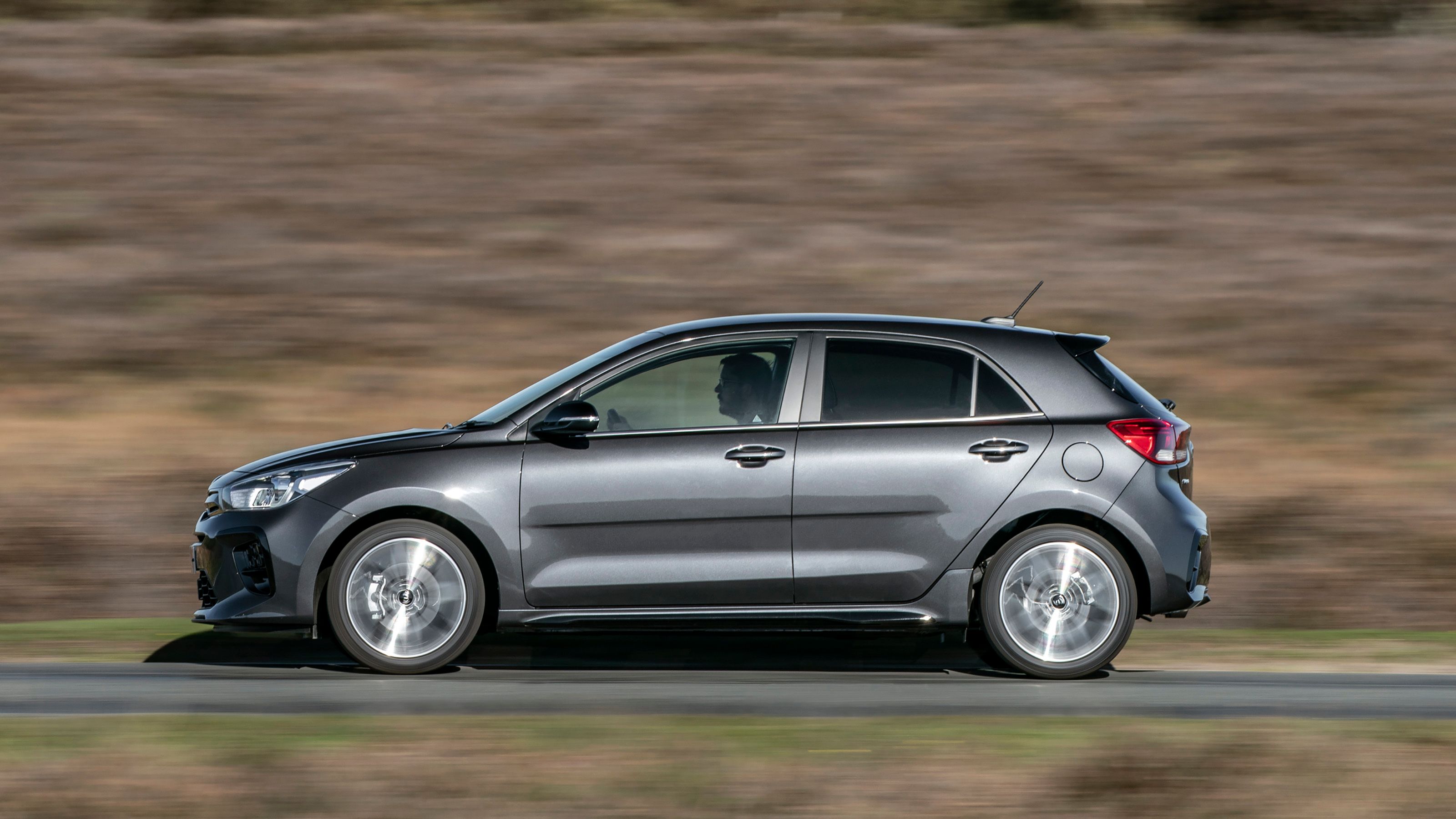 Grey Kia Rio side driving