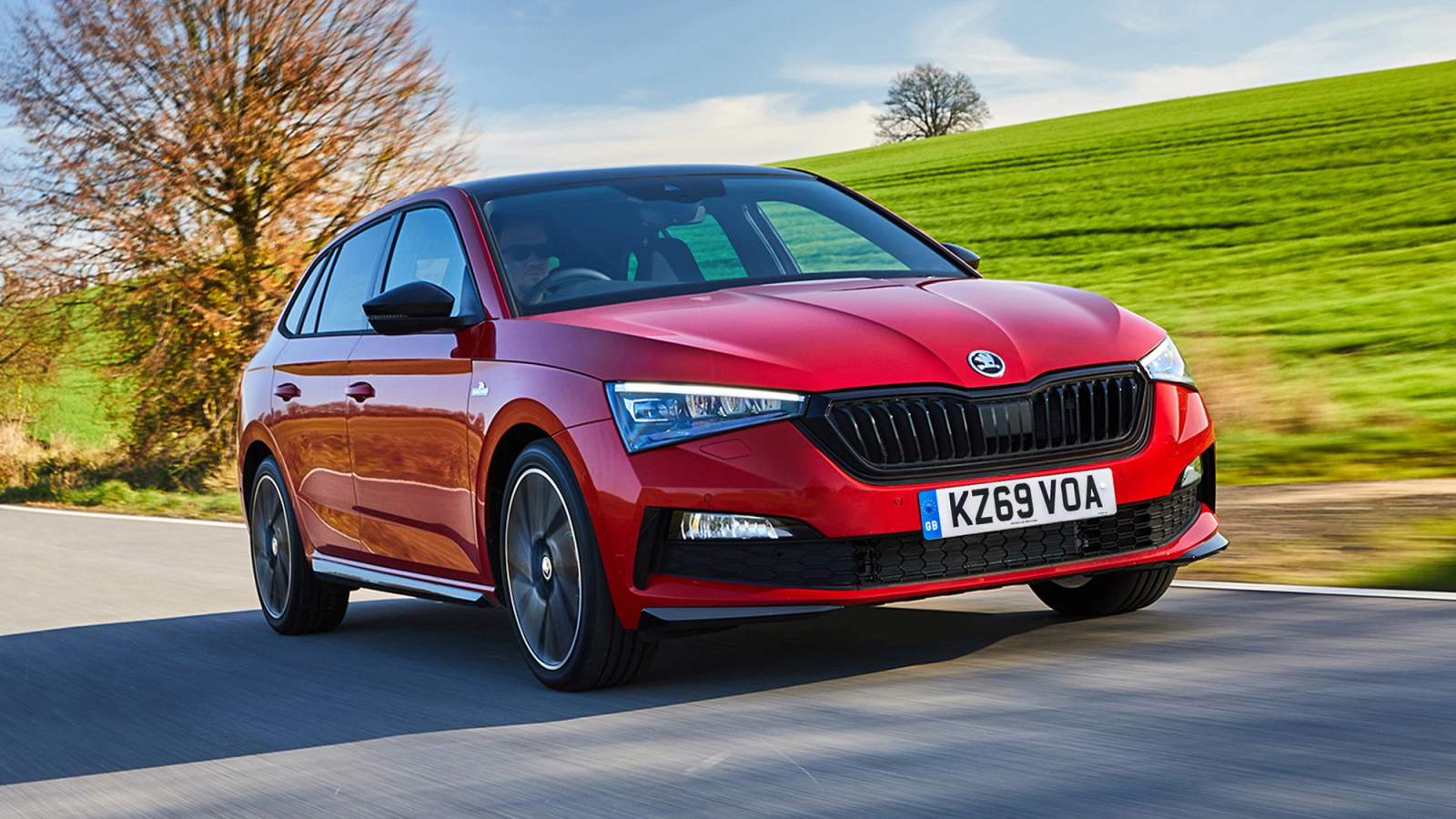 Red Skoda Scala driving on a scenic road