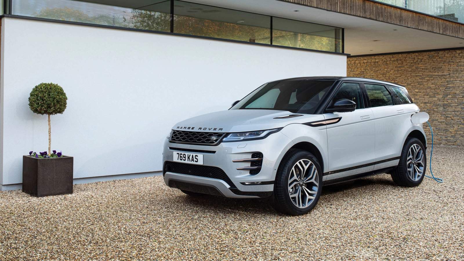 A Range Rover Evoque parked on a gravel driveway while charging