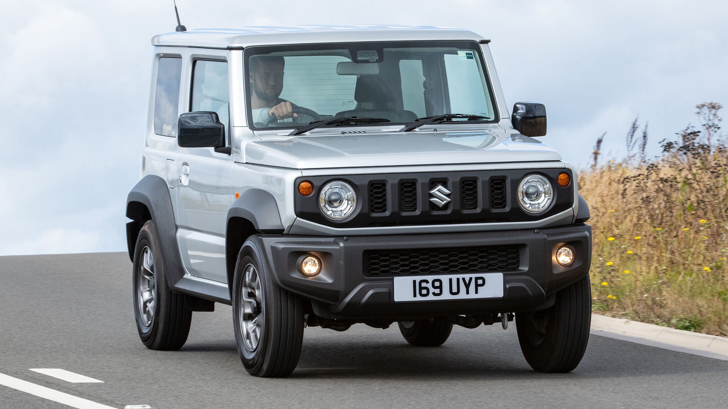 Suzuki Jimny driving on a country road on a cloudy day