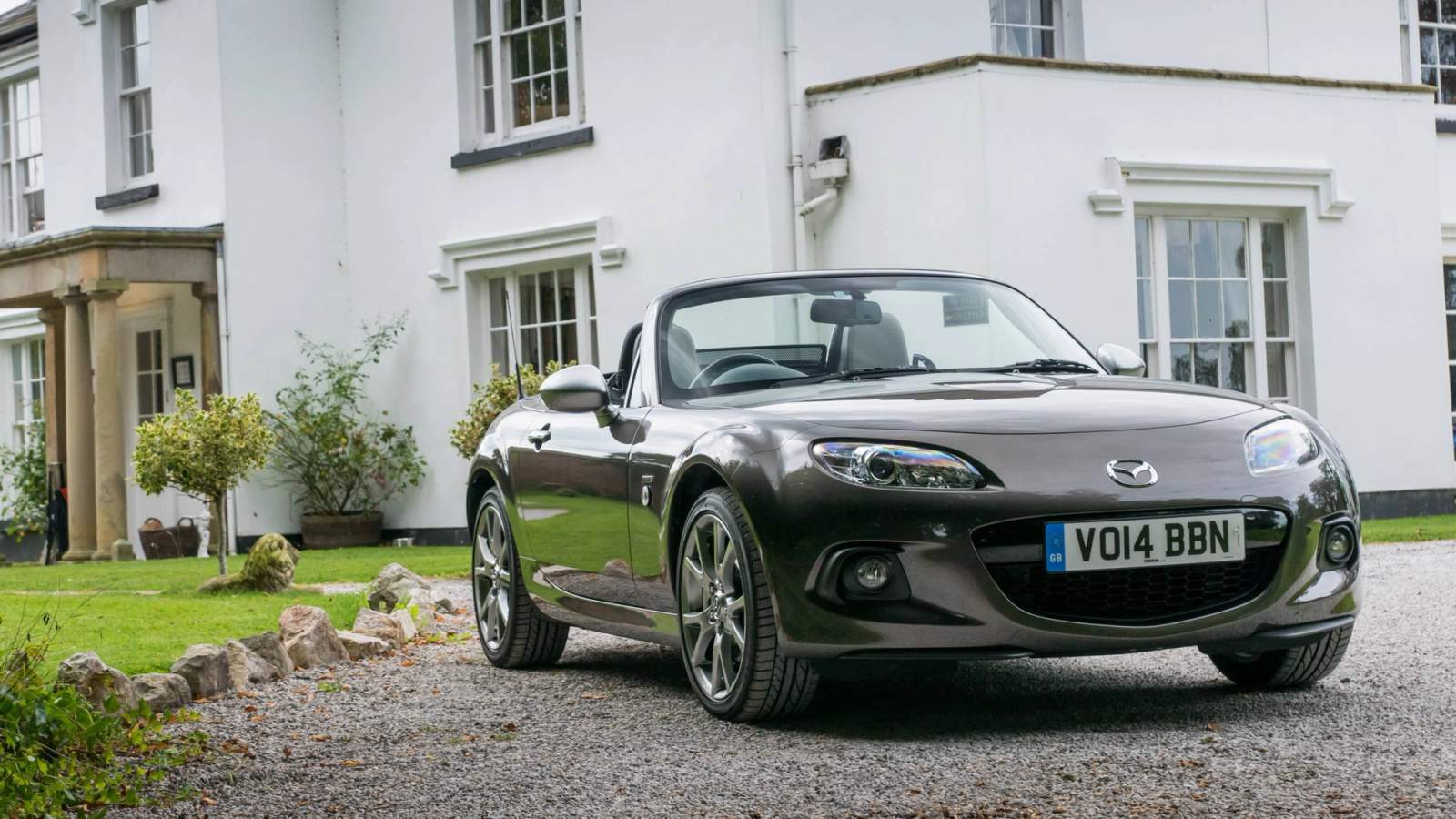 Used Mazda MX-5 parked outside a large house