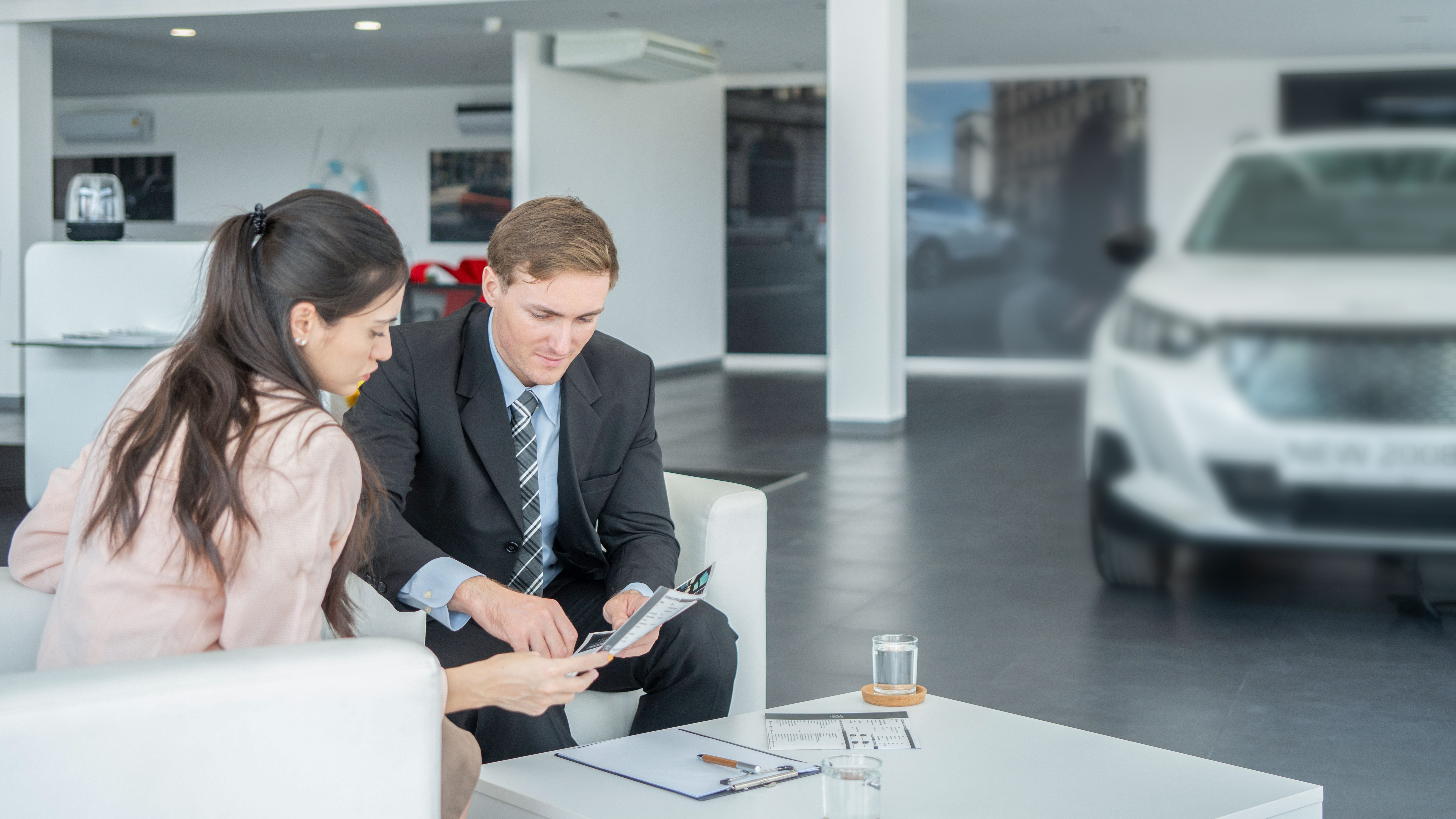 Young lady signing a document in a car dealership