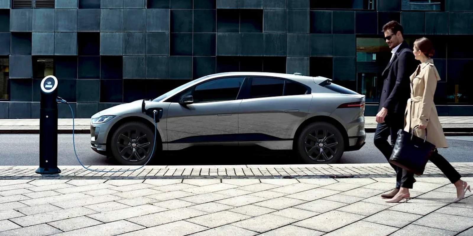 people walking past electric car on charge