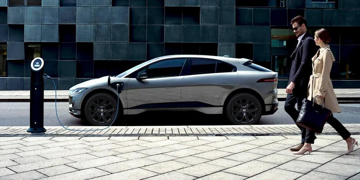people walking past electric car on charge
