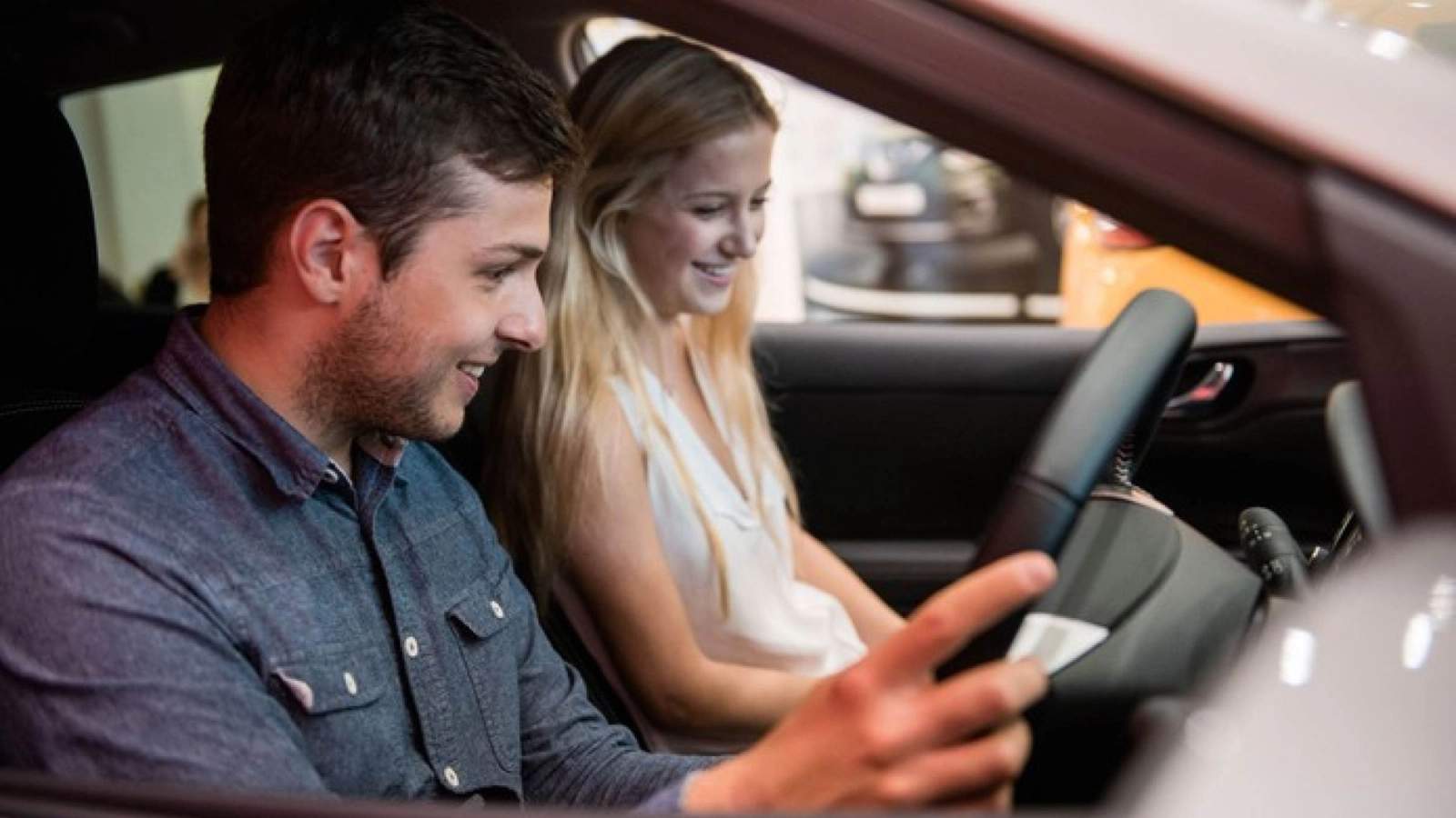 Man and woman sitting in a car in a showroom