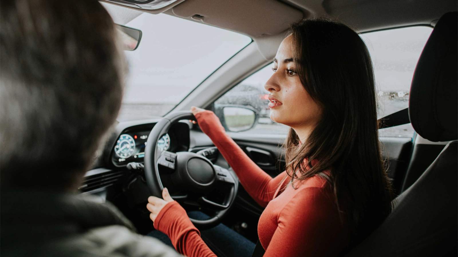 A young woman looks over the steering wheel while driving