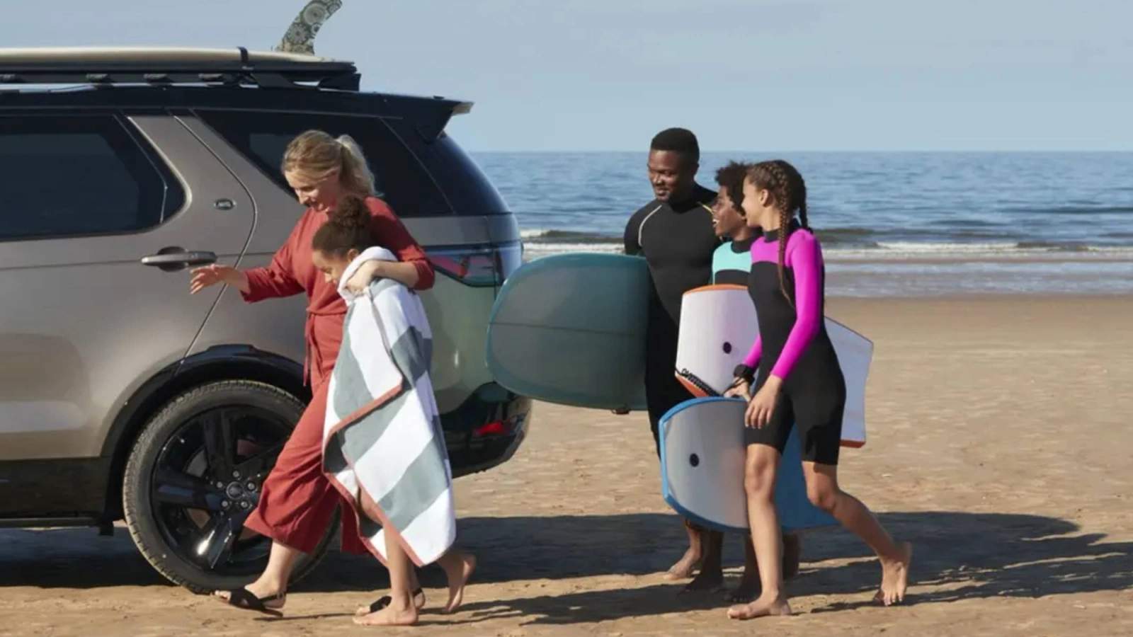 Land Rover Discovery with a family holding body boards