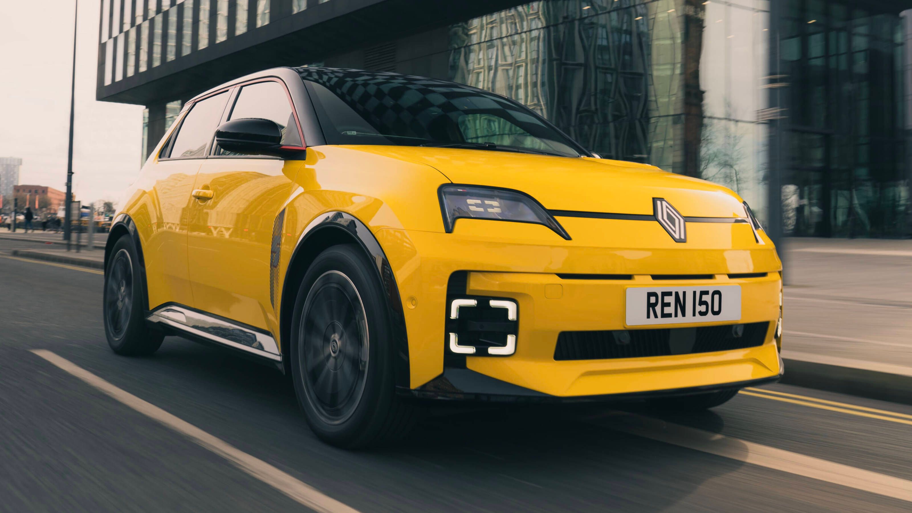 Yellow Renault 5 E-Tech driving through the city