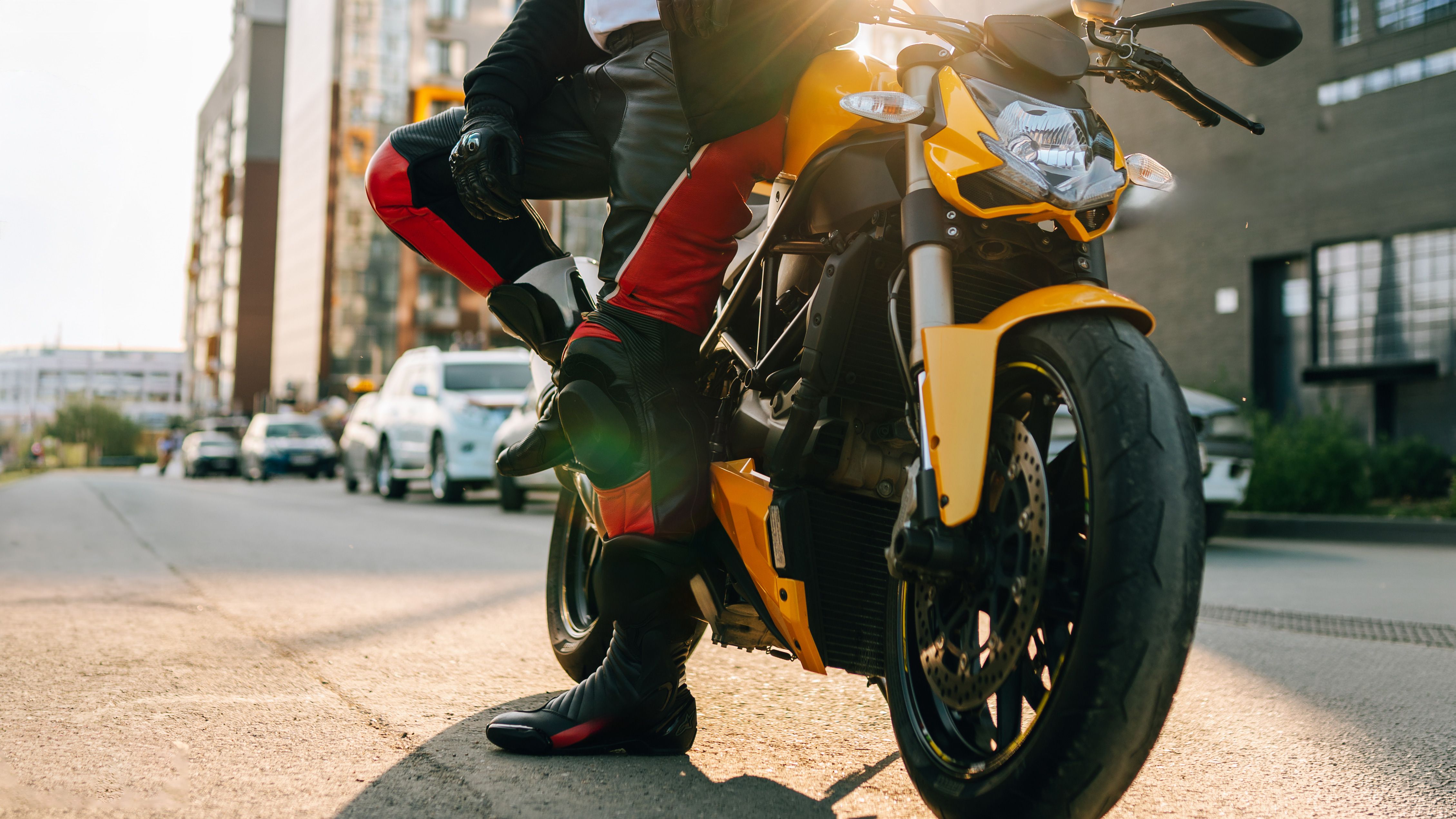 Man standing with motorbike trousers next to bike