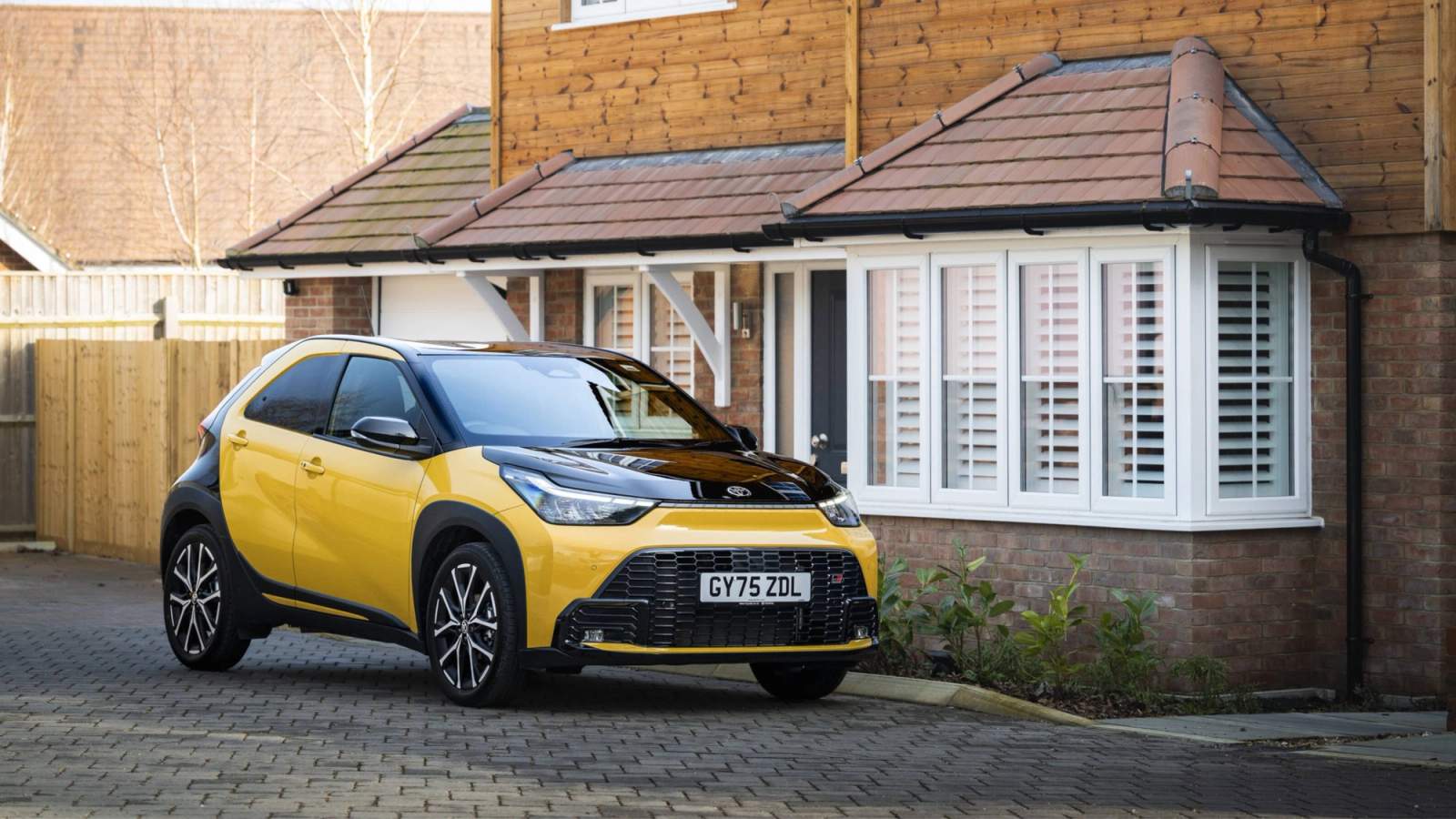 Yellow Toyota Aygo X parked outside a house