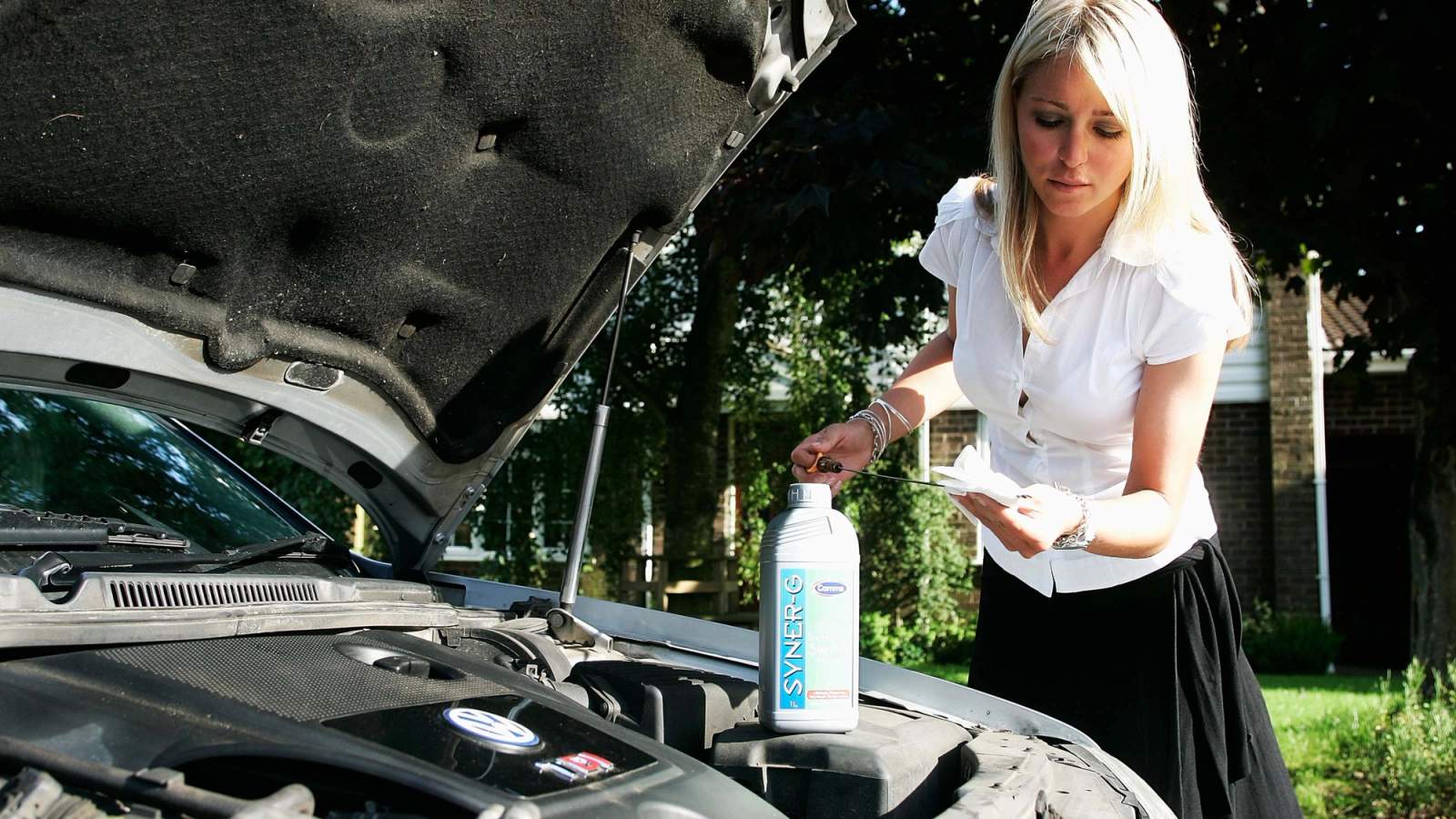 Woman checking a car's oil level by looking at the dipstick