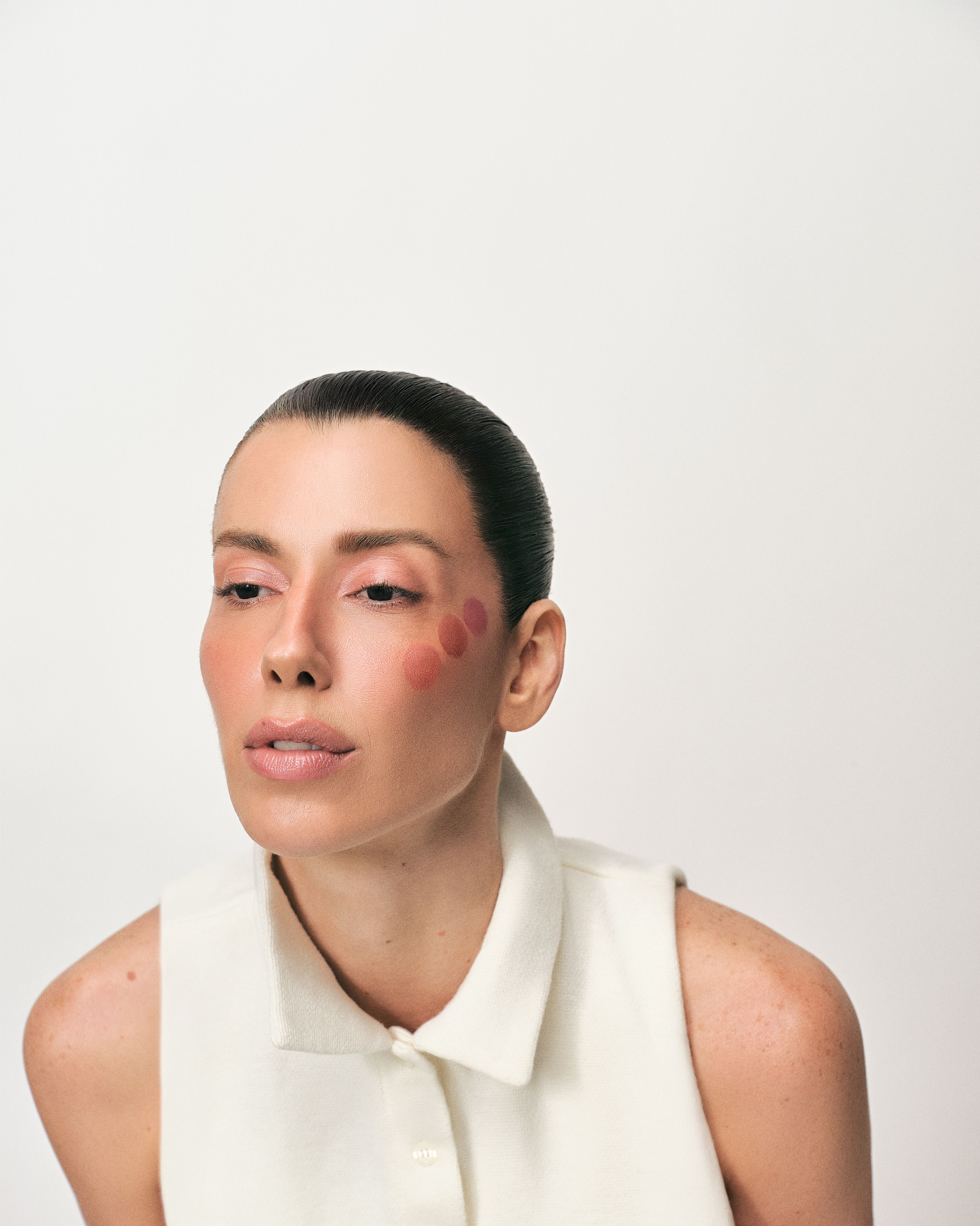 Modelo com bolinhas de blush ADCOS aplicadas na bochecha, antes de esfumar
