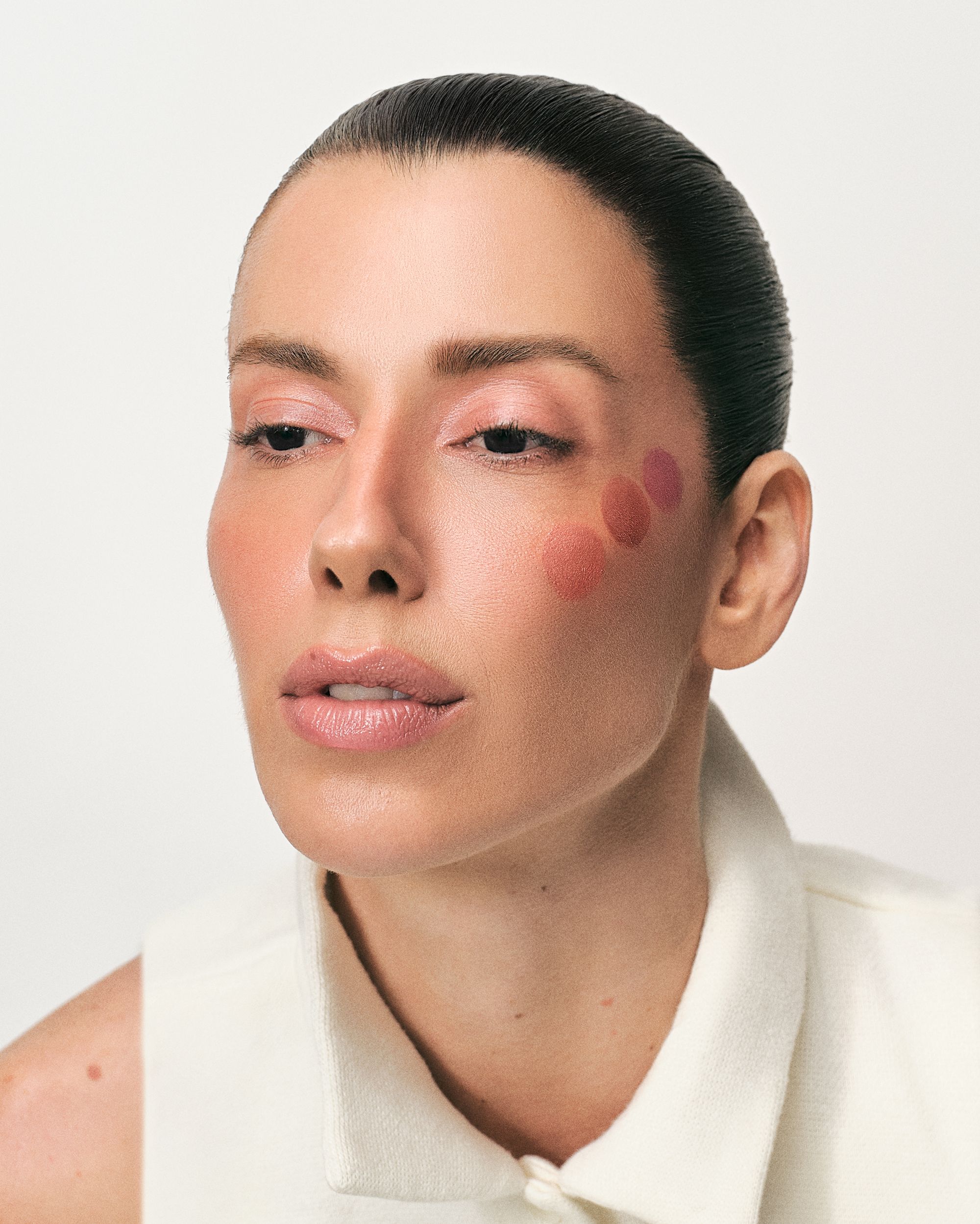Modelo com bolinhas de blush ADCOS aplicadas na bochecha, antes de esfumar