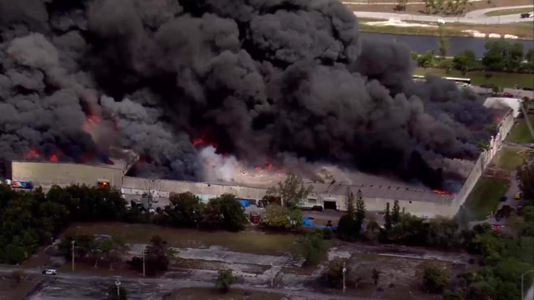 Massive warehouse fire sends thick black smoke into the sky as Miami-Dade Fire Rescue units battle the five-alam blaze at Global Warehouse Solutions.