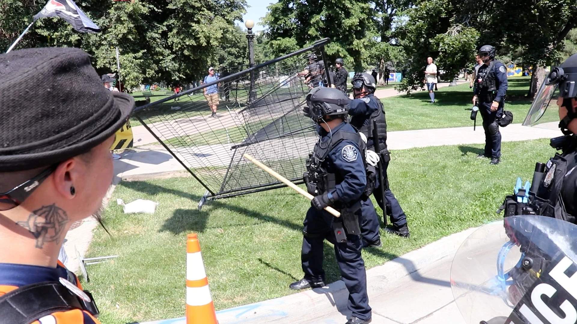 Protesters knock down poorly placed fencing prompting riot cops to scramble to re-erect it.