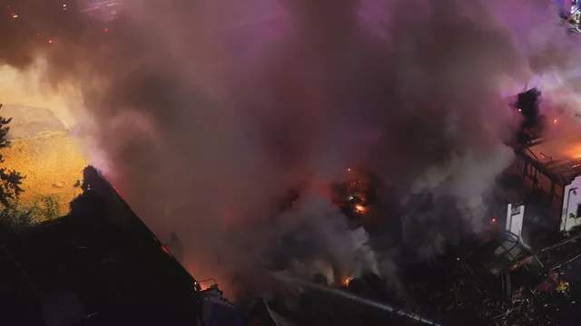 Drone aerial view of a warehouse fire with thick smoke and visible flames. Representative image of the type of fire that occurred at the Raytheon building in Warner Robins, Georgia on April 13, 2026.