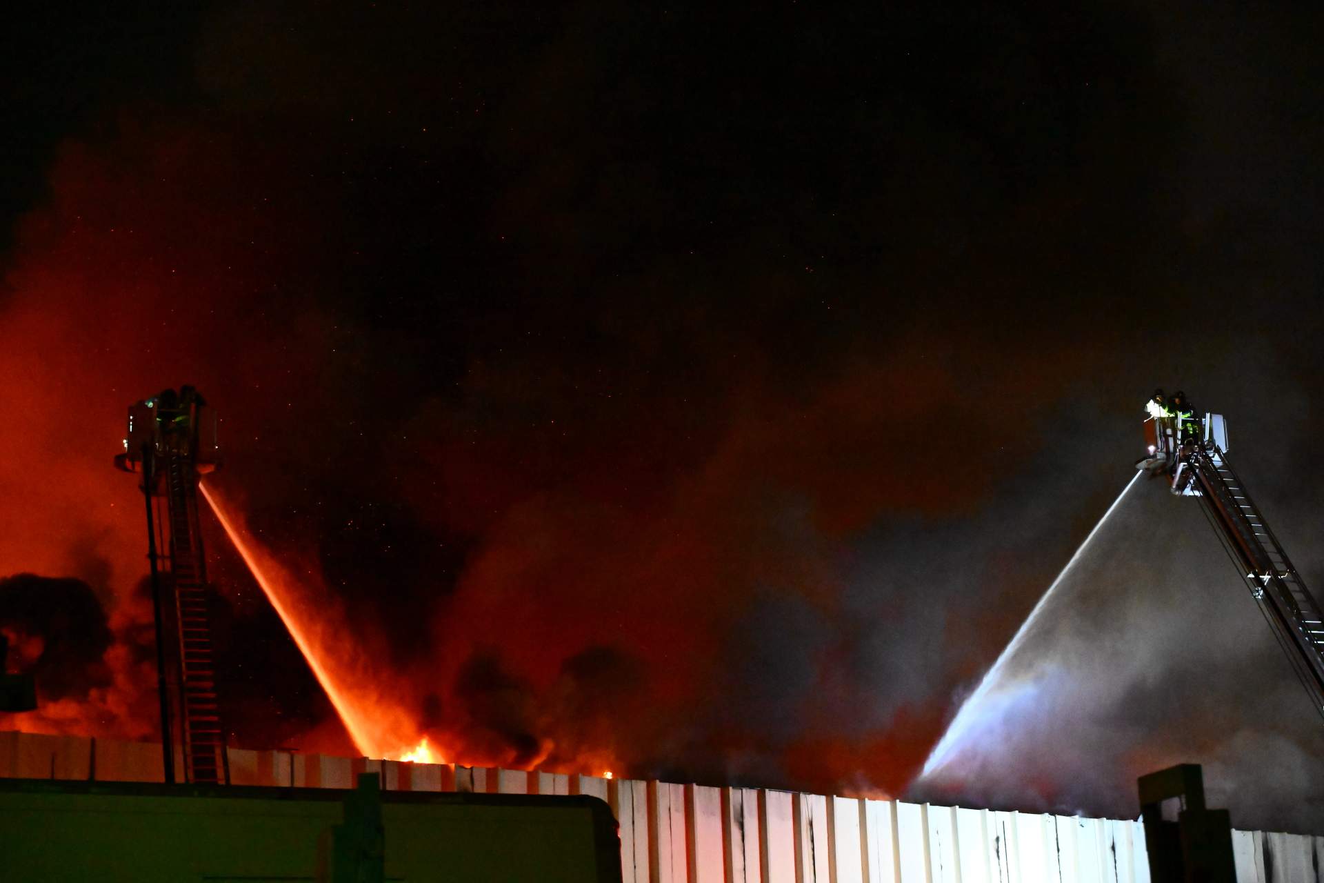 FDNY crews maintain an exterior attack on the lumberyard blaze, with water streams from multiple tower ladders dousing the intense flames that consumed the building.