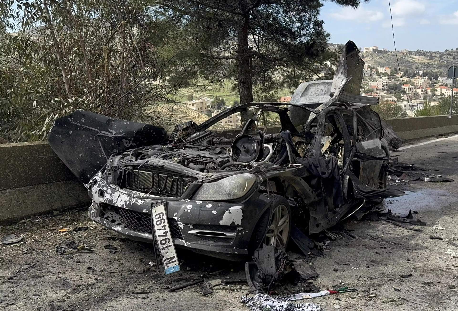 A journalist carries burned safety gear from a car that was hit by an Israeli airstrike, which killed three journalists in south Lebanon on March 28, 2026.