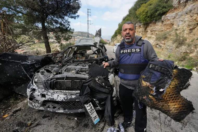 A journalist carries burned safety gear from a car that was hit by an Israeli airstrike, which killed three journalists in south Lebanon on March 28, 2026.