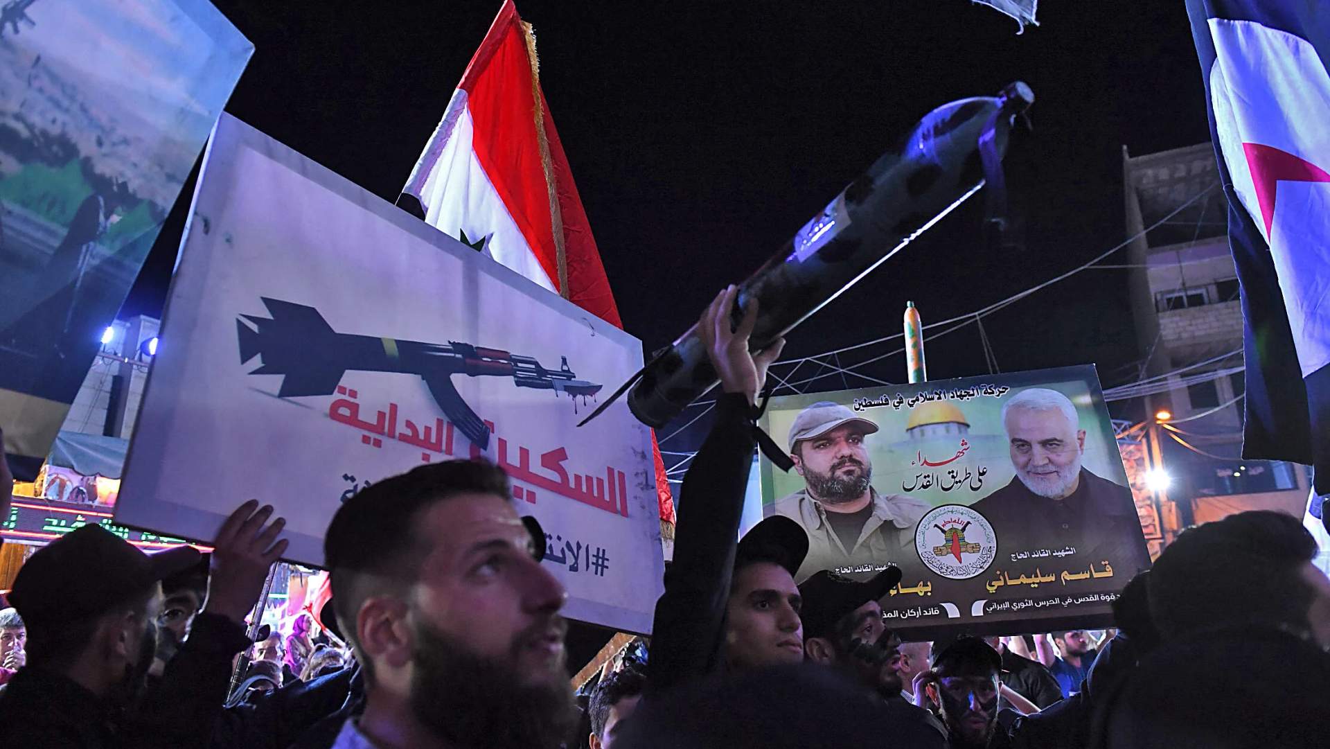Demonstrators wave the Syrian flag and lift a placard depicting slain Iranian Revolutionary Guards commander Qasem Soleimani (R), Aleppo, on May 7, 2021