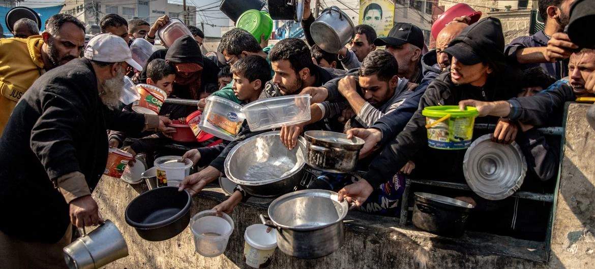 Displaced Palestinians wait for food at Al-Shaboura camp in Rafah on December 22, 2023.