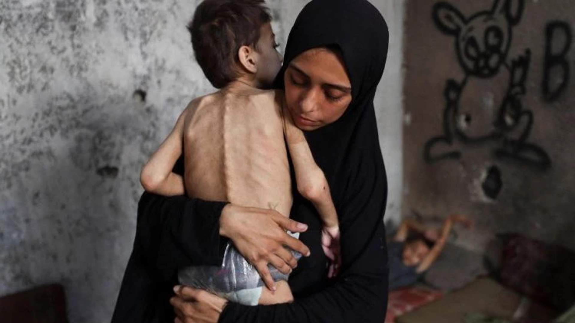 A mother in Gaza holds her starving young boy
