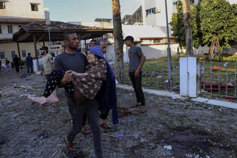 A man carries an elderly woman near Al Quds hospital after an Israeli airstrike