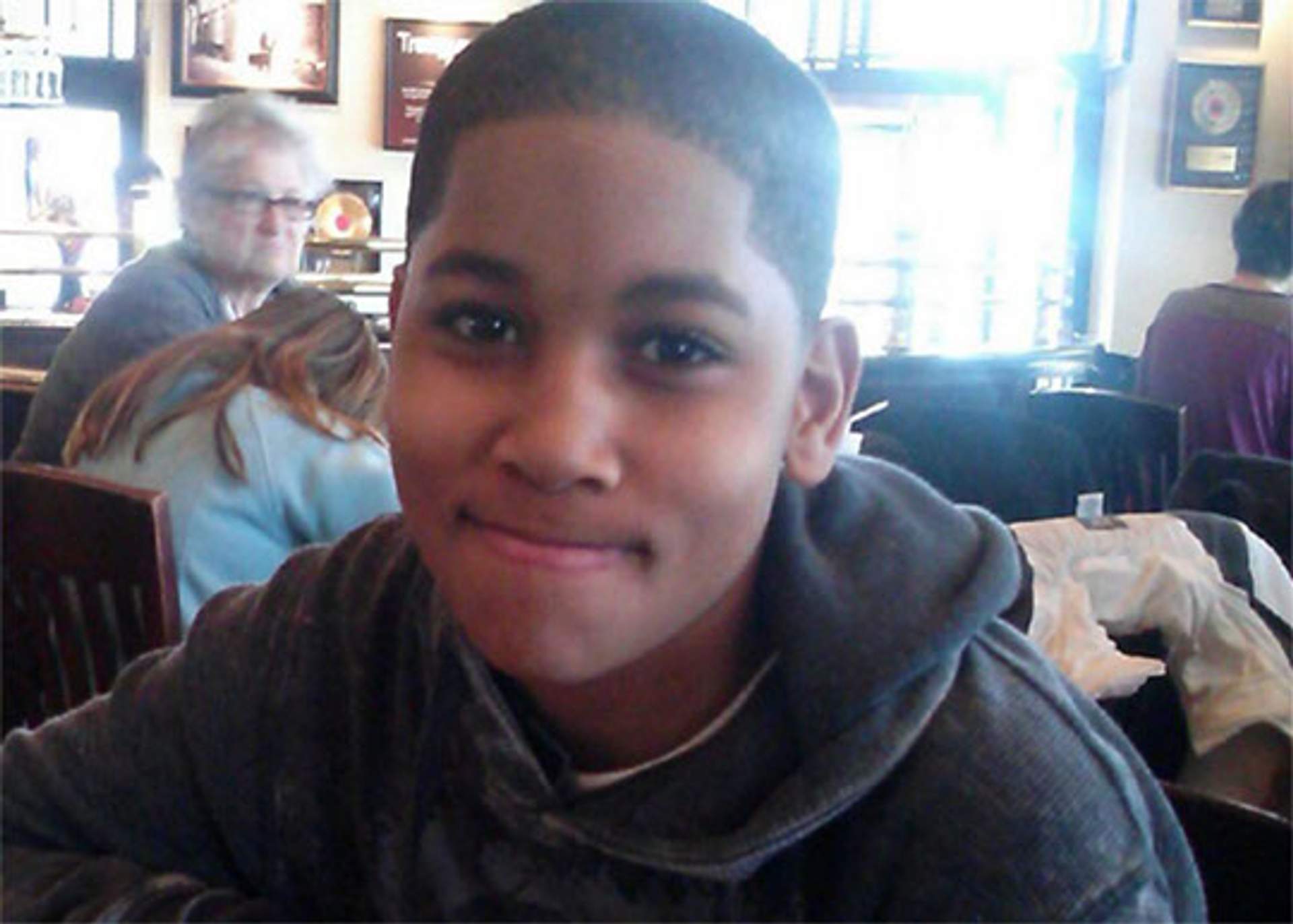 Portrait of Tamir Rice, smiling, seated in a restaurant.
