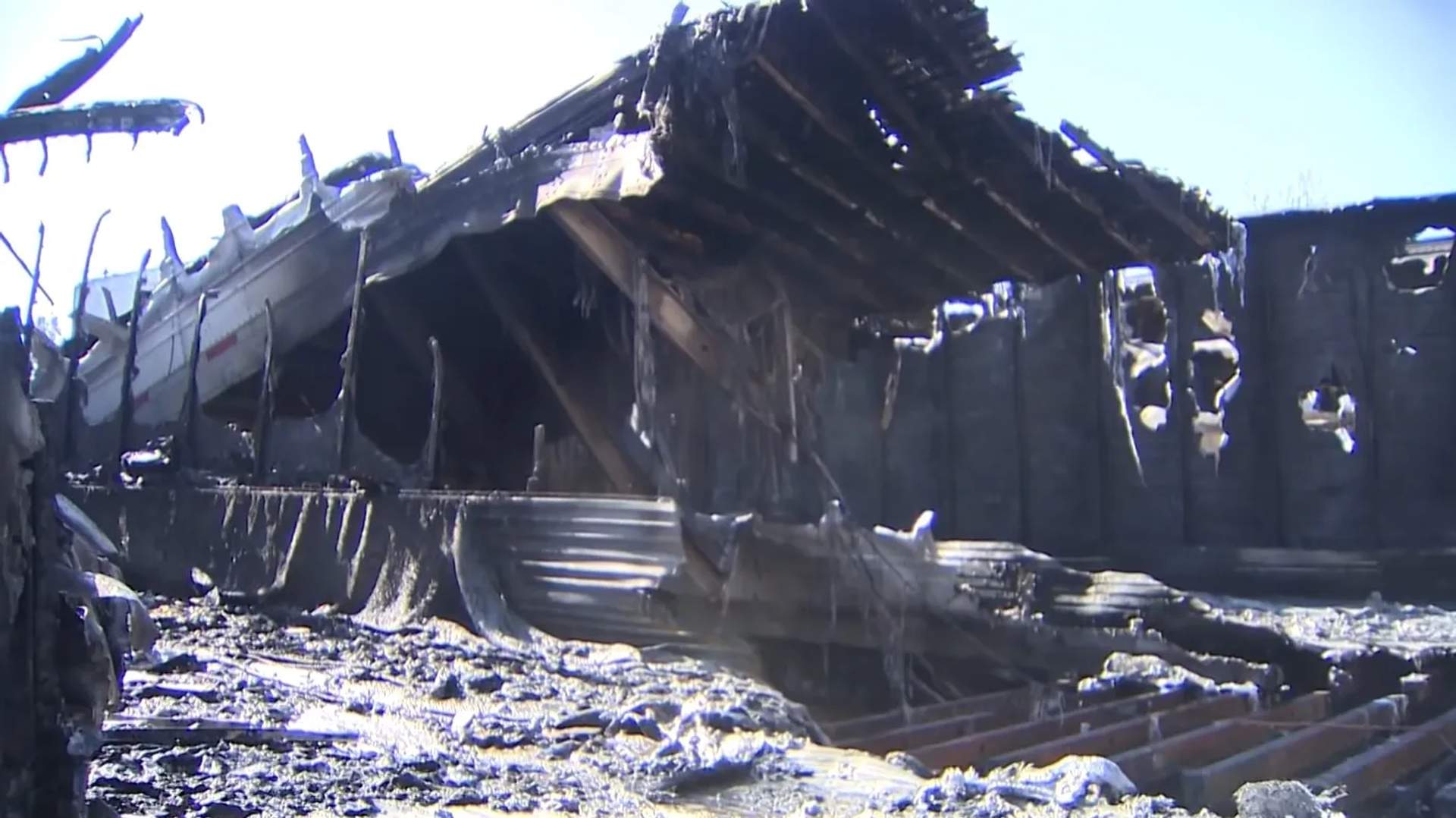 Multiple tractor trailers lined up completely destroyed by fire.