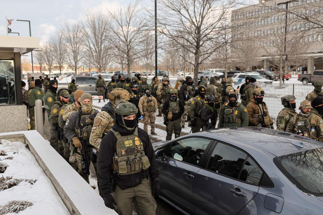 Federal agents in tactical gear standing outside a government building in Minneapolis during immigration enforcement operations