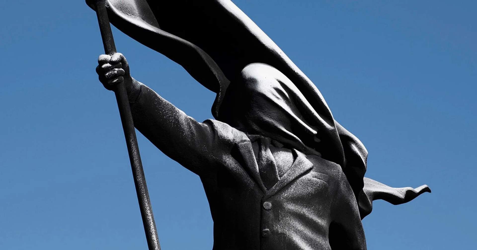 Flag drapes the face of the suited figure close up.