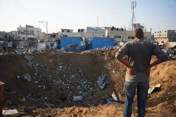 Palestinians inspect the scene of an Israeli airstrike near Al-Aqsa Martyrs Hospital in Deir al-Balah, where an overnight strike destroyed medicine storage warehouses