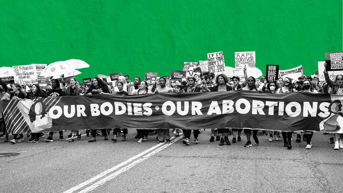 Our bodies, our abortions protest banner with large crowd behind it.