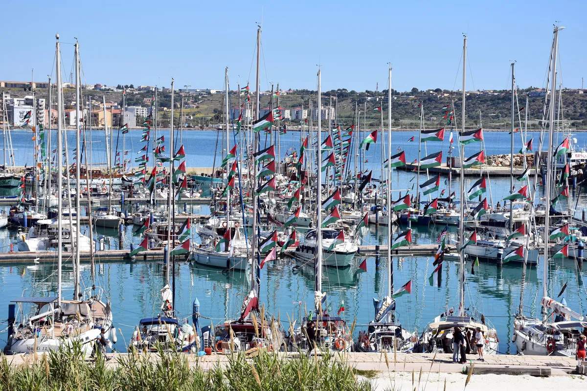 A fleet of boats sails across the open sea as part of the Global Sumud Flotilla's spring 2026 mission to Gaza. Multiple vessels, including larger ships and smaller craft, navigate the waters together in a coordinated effort to deliver humanitarian aid to Palestinians under siege.