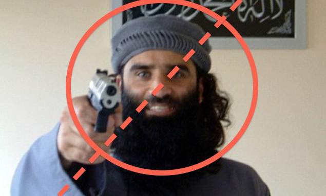 A bearded man in a beanie points a handgun at the camera, circled and crossed out with a red prohibition symbol — a stock image illustrating the 'terrorist suspect' stereotype the article critiques.