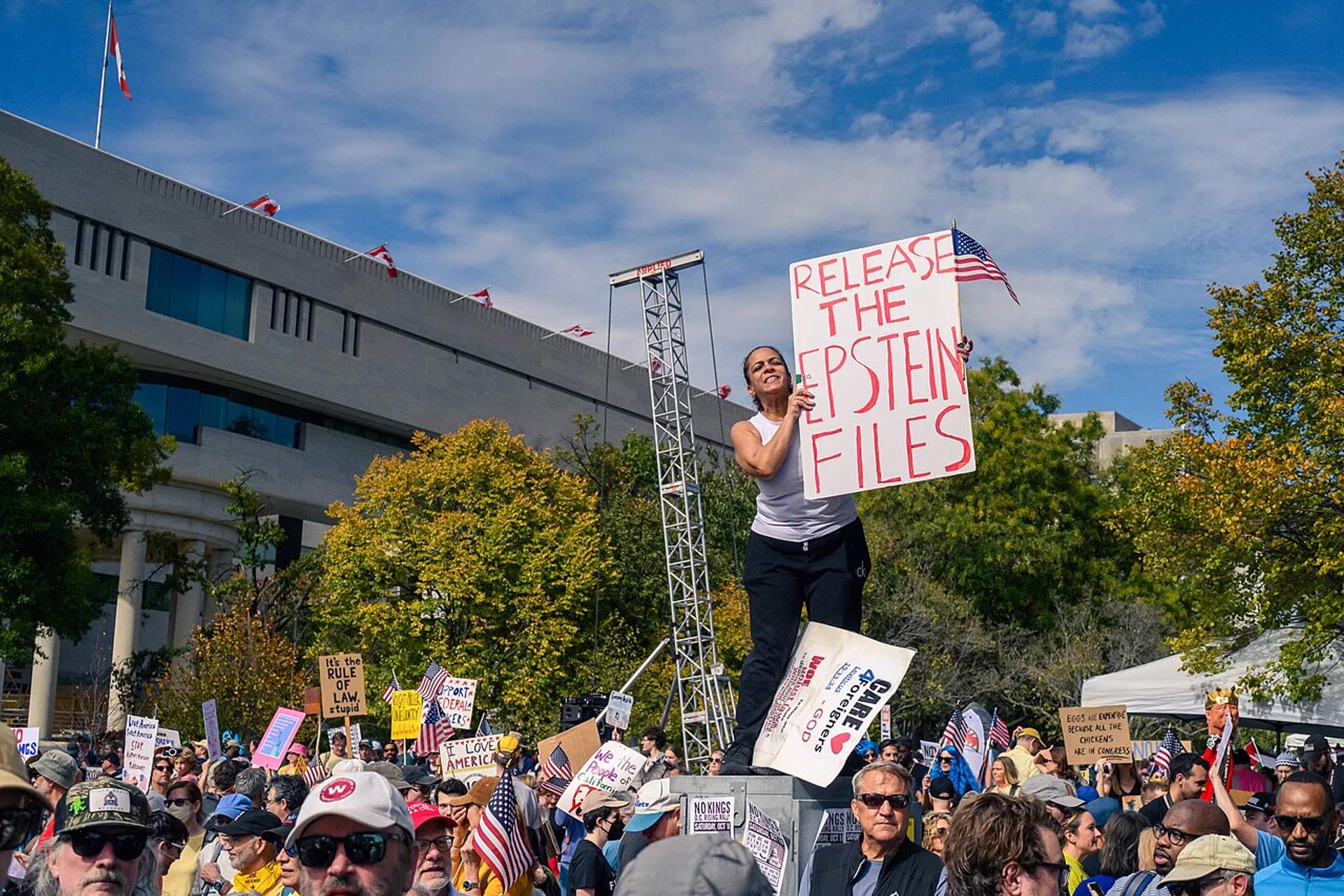 Protesters holding signs outside a government building demanding the release of the Epstein investigation files