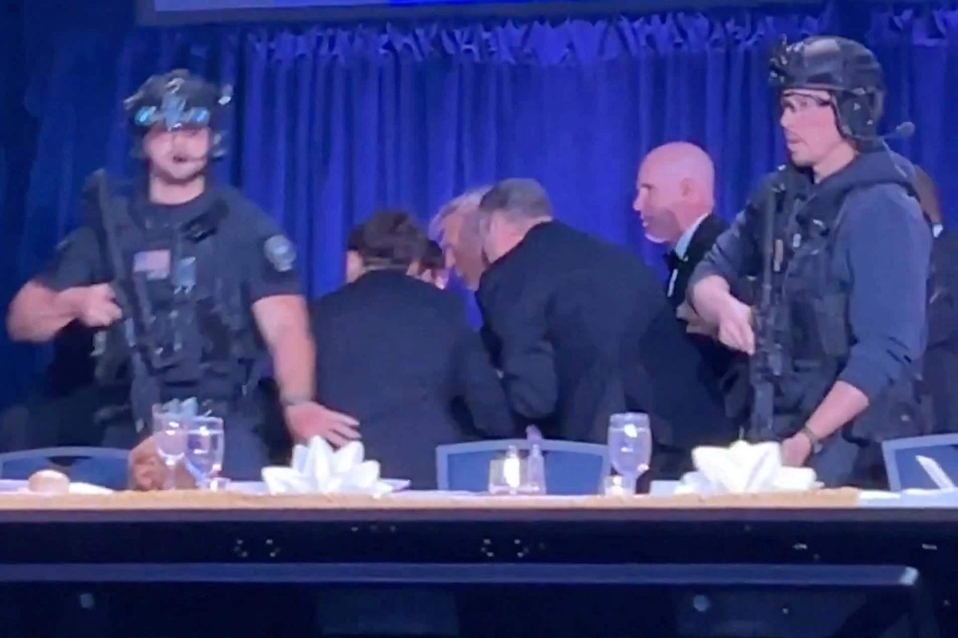 Secret Service agents with guns drawn rushing to protect and evacuate President Donald Trump at the White House Correspondents' Dinner as guests look on in the background