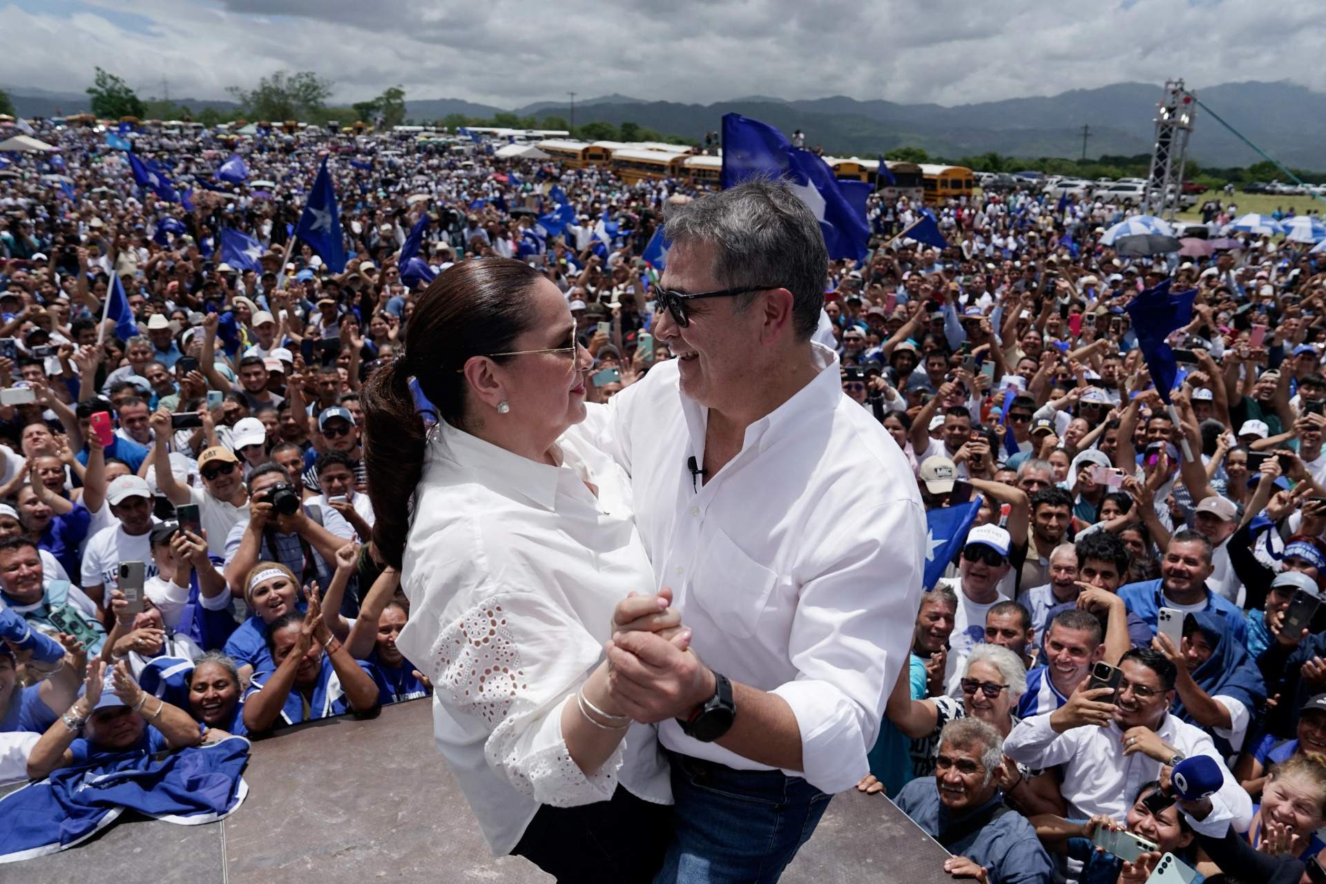 Juan Orlando Hernandez surrounded by supporters, embracing his wife, at his home in Comayagua, Honduras, gesturing as a crowd of people gather behind him on July 26, 2026