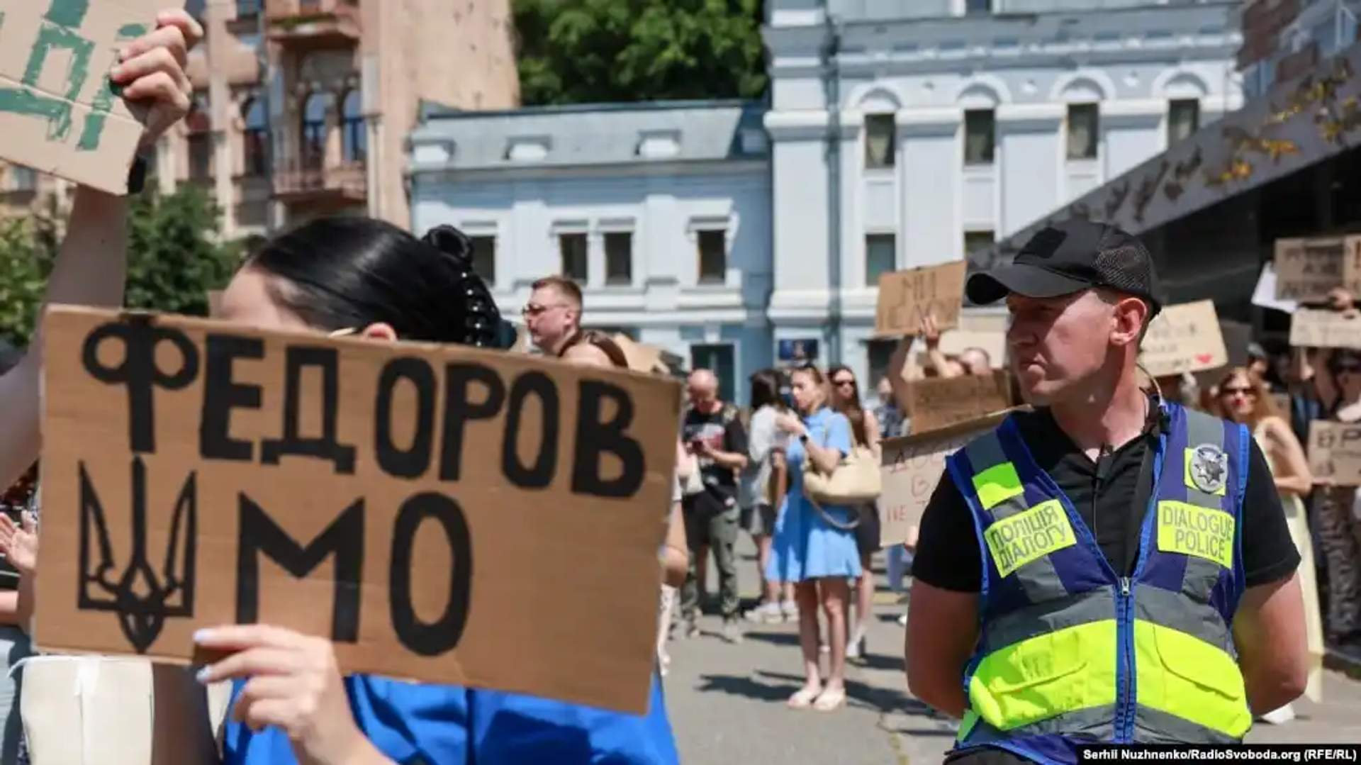 Crowd of protesters in central Kyiv holding cardboard signs near Ivan Franko Theater