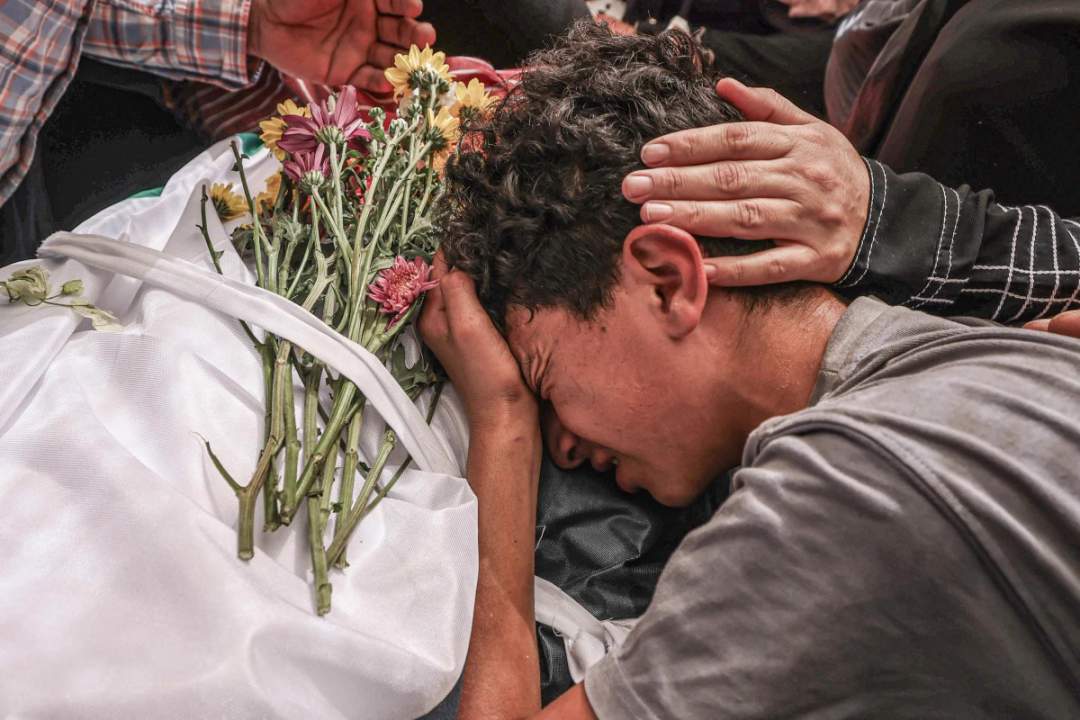 Palestinian mourners in black carrying the body of 17-year-old Fadi al-Naasan on a stretcher through a dusty street during his funeral in al-Mughayyir, occupied West Bank, July 18, 2026