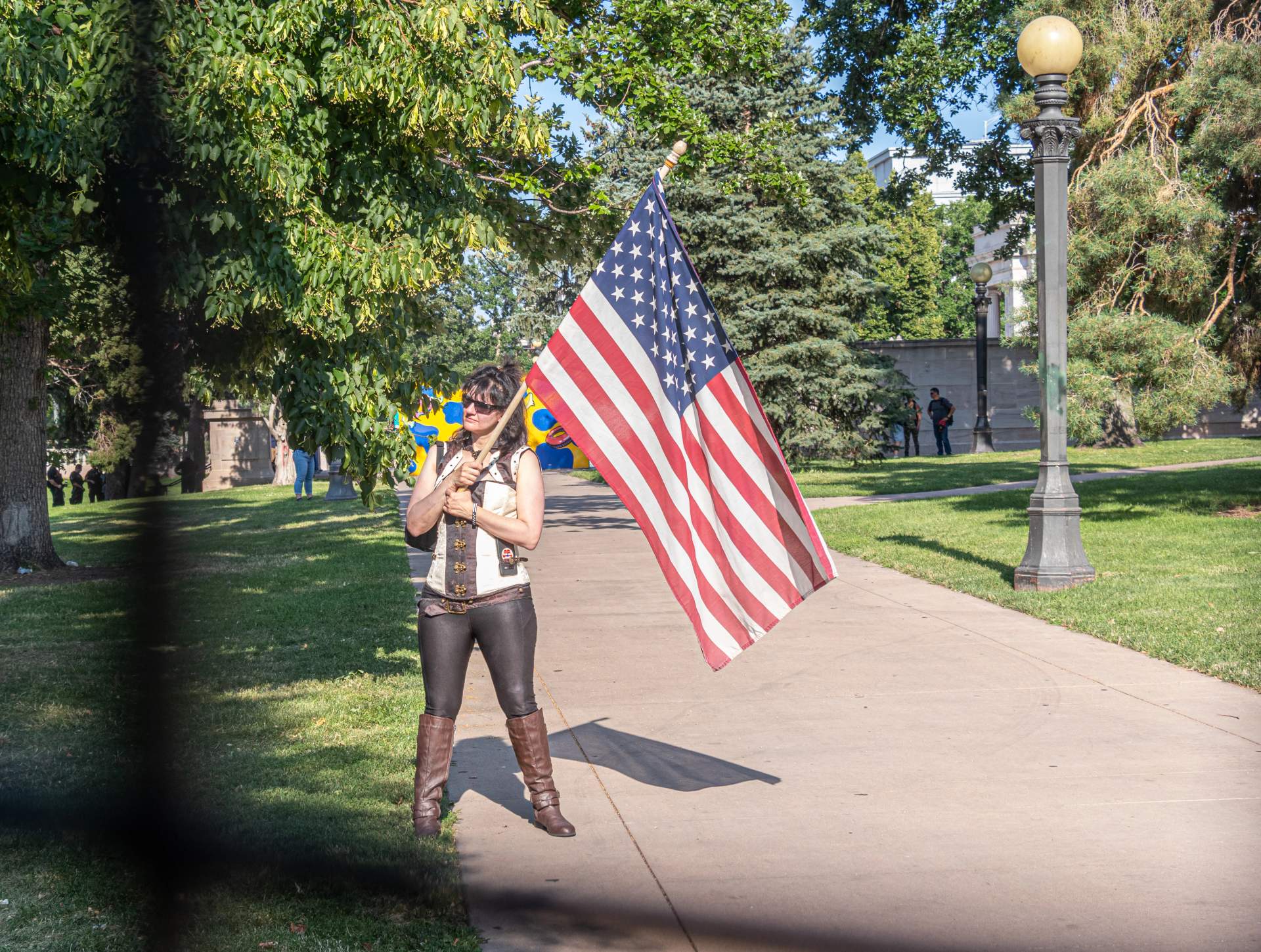 A supporter waves an american flag at protesters from behind the fence.