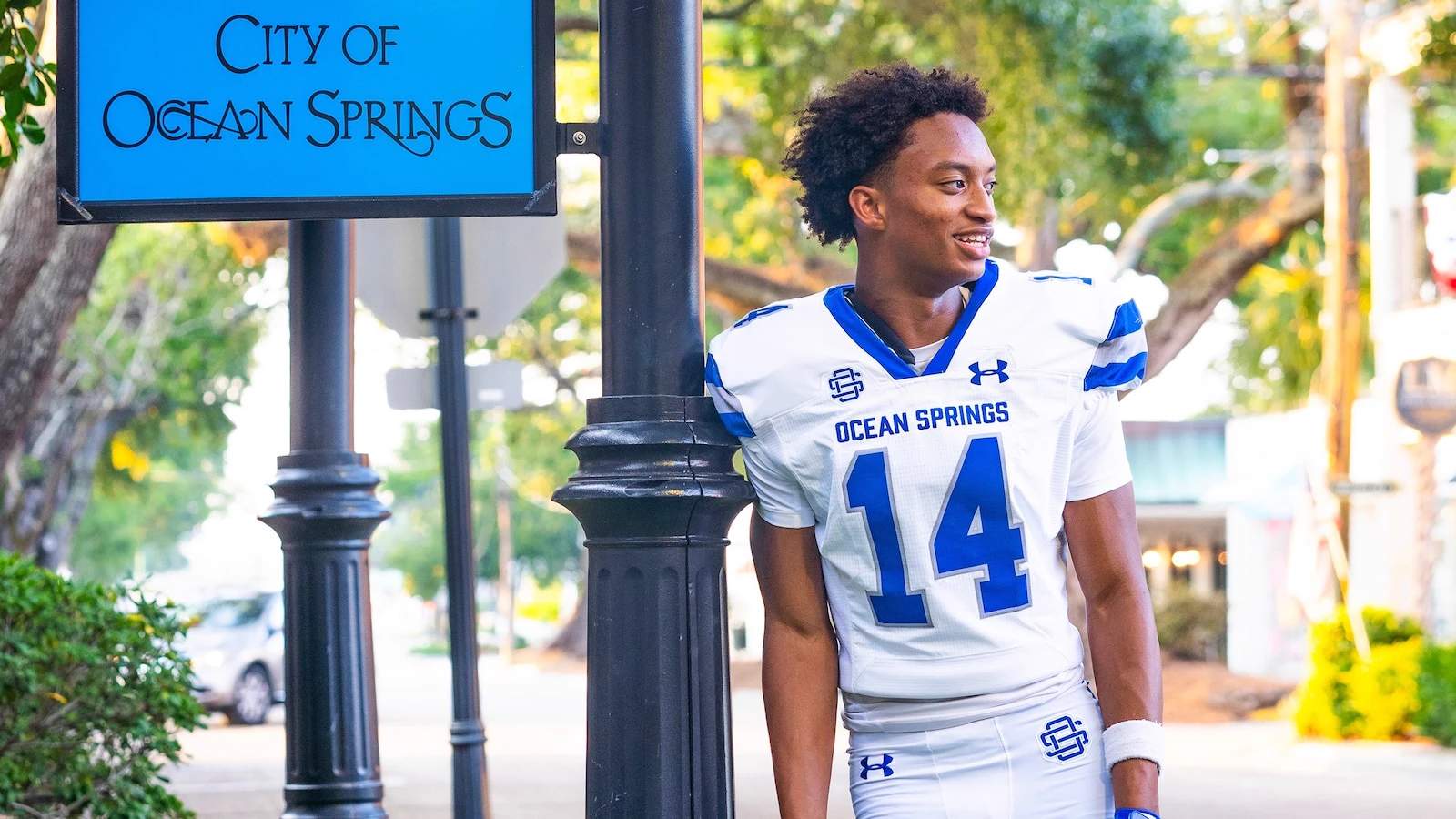 Nolan Xavier Wells poses in his Ocean Springs high school football uniform, next to a City of Ocean Springs sign.