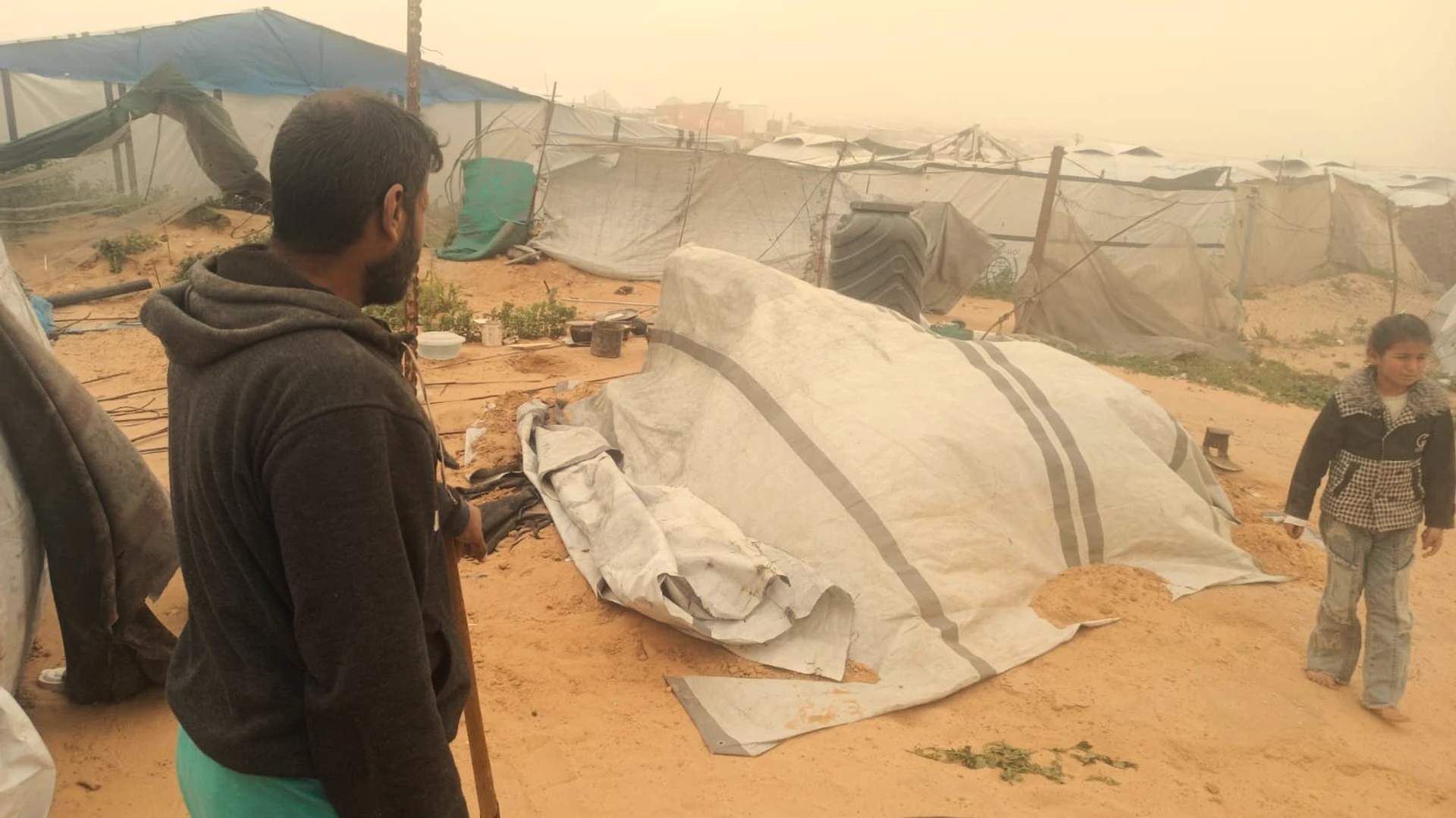 Rows of makeshift tents and shelters for displaced Palestinians stretching across sandy terrain in Khan Younis