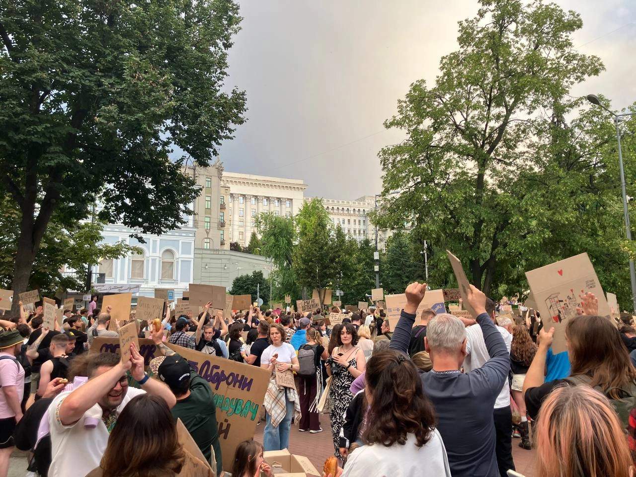 Large crowd of young protesters holding cardboard signs outside the Presidential Office in Kyiv at night