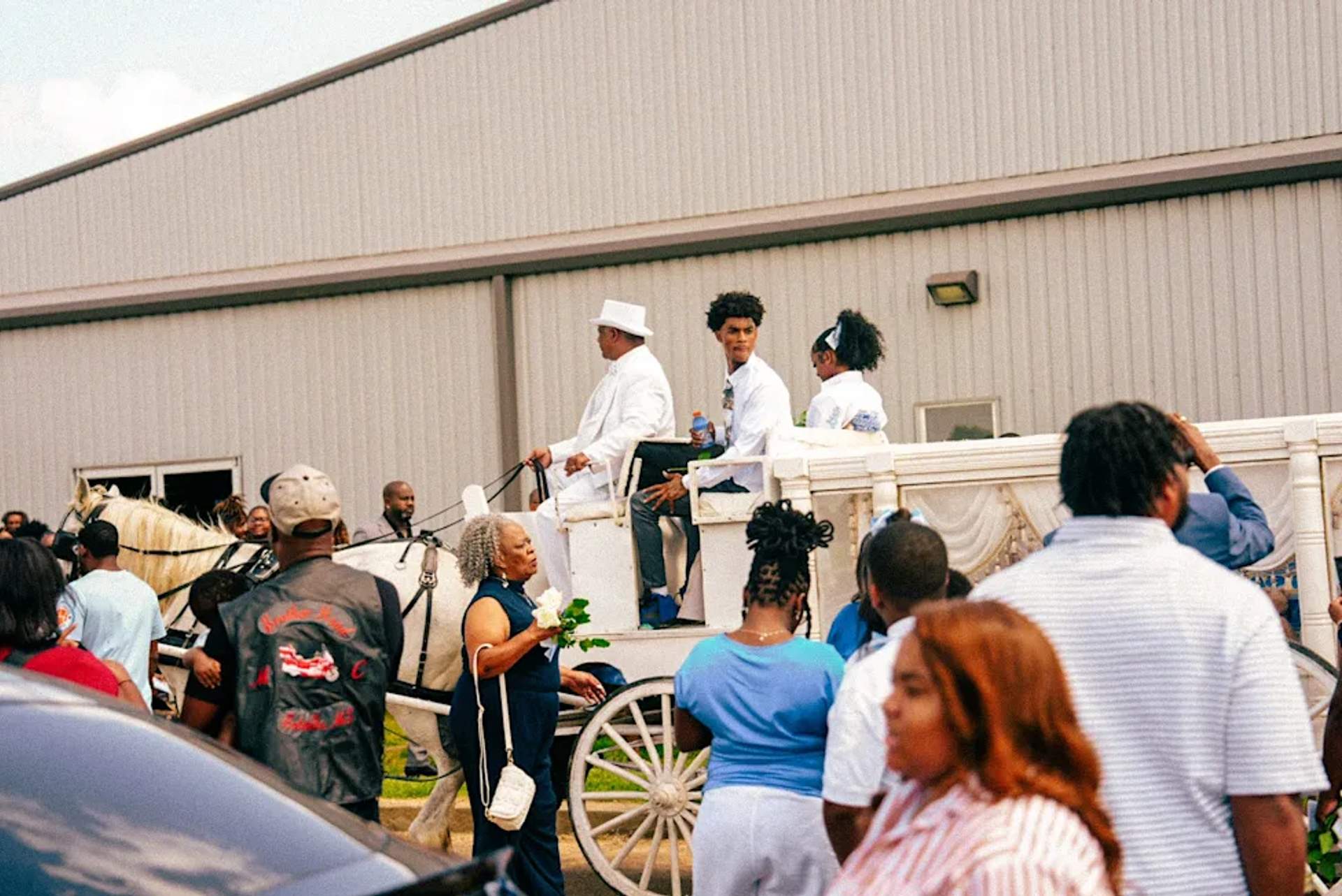 A crowd of mourners dressed in teal and blue gather outside the Hosanna Family Worship Center in Pope, Mississippi for the funeral of one-year-old Kohen Wiley on June 27, 2026